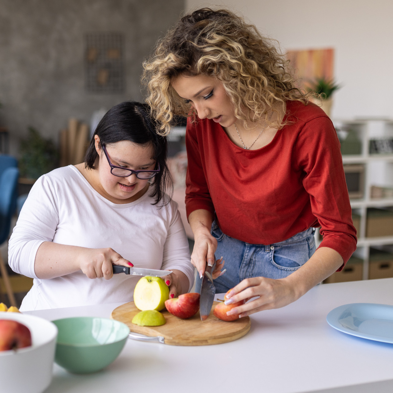 Zwei Frauen schneiden Äpfel auf einem Schneidebrett