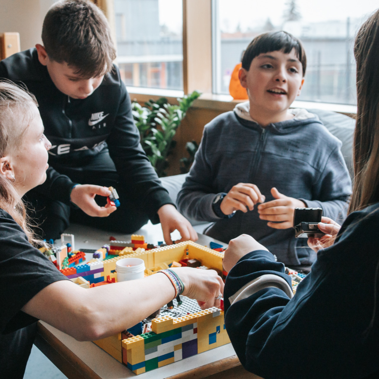 Mehrere Kinder sitzen nebeneinander und spielen mit Lego